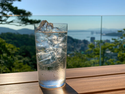 refreshing glass of iced water on sunny wooden table with breathtaking coastal view blurring in background perfect for summer thirst beverage hydration outdoor dining and scenic hospitality concepts