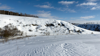 Fototapeta premium Snow blankets rolling hills under bright blue sky