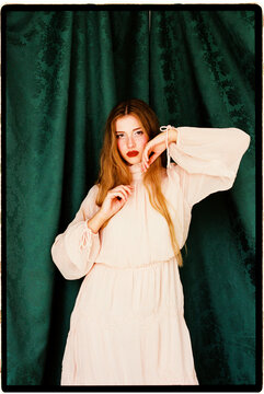Woman posing against green damask curtain
