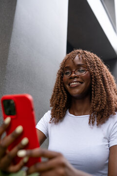 Curly woman checking smartphone in outside cafe