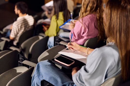 A student attends a classroom lecture and takes notes.