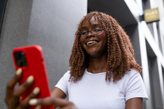 Curly woman checking smartphone in outside cafe