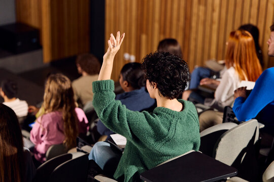 Student raises her hand in an auditorium.