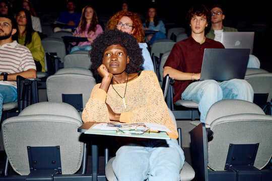Woman sits in an auditorium among other students