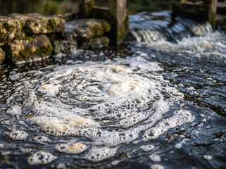 Fototapeta premium Swirling Foam Vortex And Current At River Cascade Weir