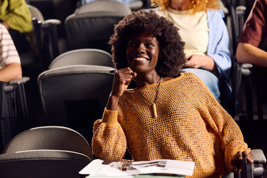 Beautiful woman sits in an auditorium, smiling