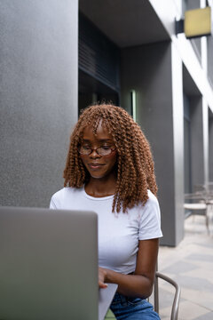 Gen Z professional working on laptop at outdoor cafe