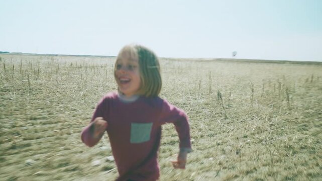 Boy running through open prairie field then siblings embracing in golden grass
