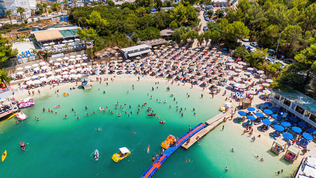 Aerial drone view of the famous Bora Bora beach bar, sandy cove, and turquoise water in Ksamil, Albania
