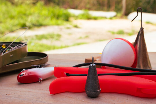 Fishing tackle and equipment for outdoor leisure activity, with lures, sinker, bobber, and tackle box on a wooden surface, ready for angling and recreation