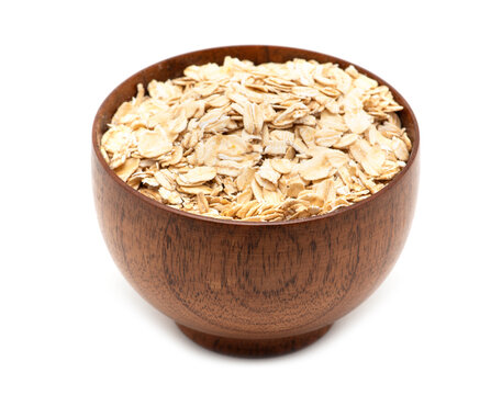 Oats spilling from wooden bowl.