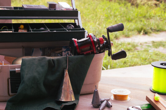 Fishing tackle box filled with various angling gear, including reels, lines, lures, weights, and tools, preparing for an outdoor hobby and vacation activity
