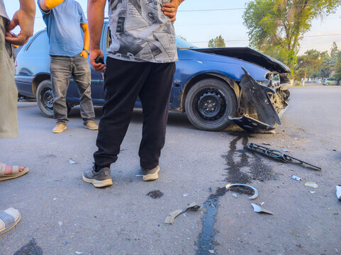 Group of Men Assessing Damaged Blue Car on Road
