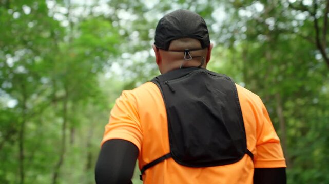 Determined man trail running through a forest during an extreme outdoor workout. He pushes his limits while pursuing fitness goals, endurance personal achievement through an active healthy lifestyle.
