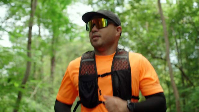 Determined man trail running through a forest during an extreme outdoor workout. He pushes his limits while pursuing fitness goals, endurance personal achievement through an active healthy lifestyle.
