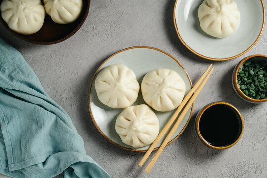 Steamed bao buns with soy sauce and green onion in a flat lay