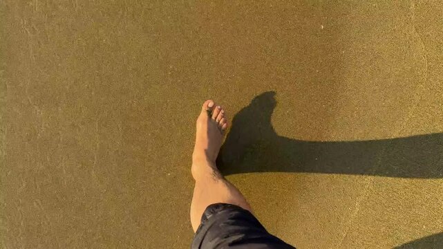 pies de un hombre caminando sobre la arena mojada a la orilla del mar en la playa relajado paso a paso sintiendo libertad y tranquilidad en un dia soleado en la naturaleza 