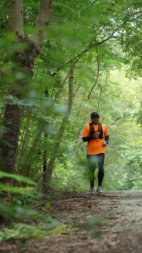 Determined man trail running through a forest during an extreme outdoor workout. He pushes his limits while pursuing fitness goals, endurance personal achievement through an active healthy lifestyle.
