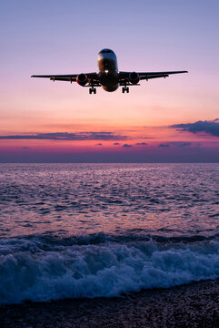 Passenger jet plane landing over the sea against the backdrop of scenic sunrise sky