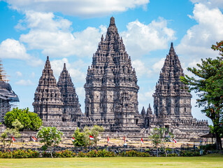 Naklejka premium Ancient Hindu temple complex standing tall under a blue sky, showcasing detailed stone carvings and intricate architecture in Sleman, Daerah Istimewa Yogyakarta, Indonesia