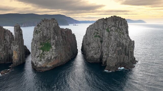Aerial view of towering columnar rock cliffs beside a broad body of wa