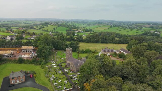 Wide aerial view of St Michael's Church of Ireland among trees with Castlecaulfield village and the Tyrone countryside beyond, Northern Ireland