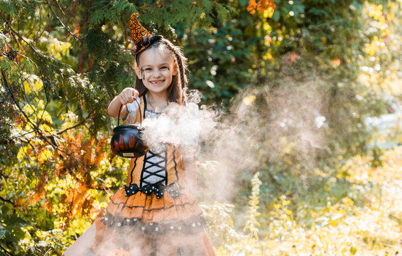Girl Enjoys Halloween Festivities in Autumn Garden With Pumpkin and Spiderwebs During October
