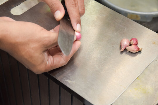 Close up shot of a man peeling unions using special peelers in the kitchen