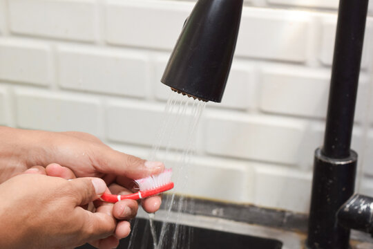 Close up a man washing toothbrush after using