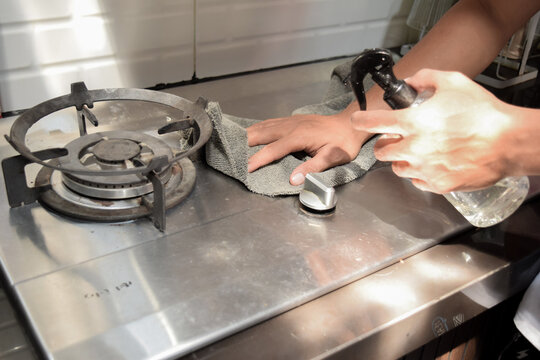 Close up shot of male hands holding bottle spray and cleaning the stove