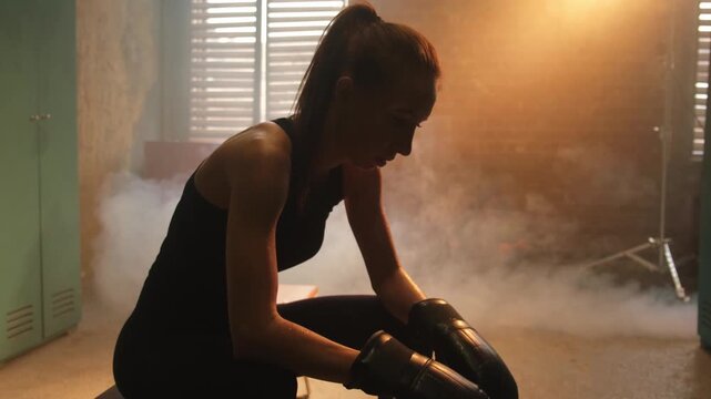 Women self defense girl power. Strong sweaty athlete woman fighter resting after fight training on boxing ring. Strong girl tired wipes sweat after training session in gym. Strength fit body workout