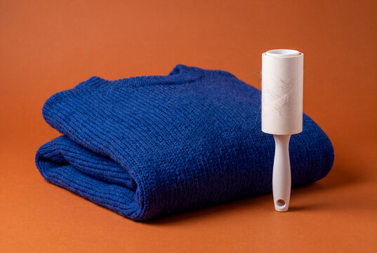 Sticky Lint Roller Next to Folded Blue Sweater for Garment Care