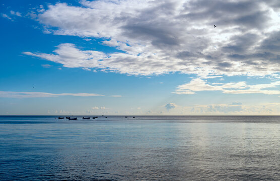 Small fishing boats resting on the calm North Sea beneath a wide dramatic morning sky at Robin Hood&rsquo;s Bay on the Yorkshire coast, North Yorkshire, England.