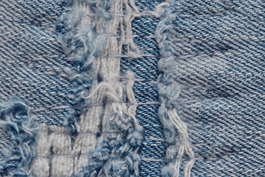 Extreme macro shot of torn denim fabric displaying frayed threads and woven cotton texture.