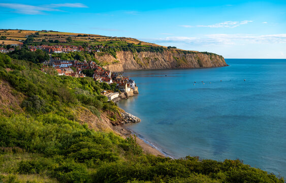 Panoramic view of Robin Hood&rsquo;s Bay with its historic fishing village, green cliffs and calm North Sea on a sunny summer day in North Yorkshire, England.