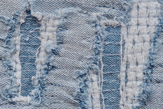 Extreme macro shot heavily distressed denim fabric showing intricate torn threads and woven structure.