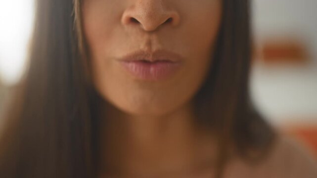 Young woman closeup of lips and chin pursing then smiling while filming subtle mouth expressions in studio; playful intimacy.