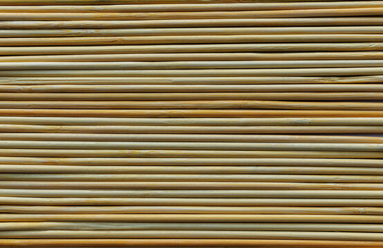 Close-up texture of dry natural reed stems arranged in parallel horizontal rows, creating a warm beige and brown linear pattern.