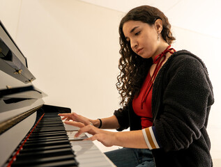 Young woman playing piano practicing music performance © Fabian Vargas