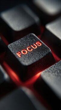 Macro close-up of a computer keyboard key glowing with red backlight and focus text. Productivity and mental concentration concept for motivational.