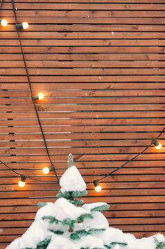 Rustic wooden backdrop with glowing lights, evergreen branches and snow