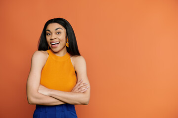 Obraz premium Beautiful African American woman smiles joyfully against a vibrant orange backdrop