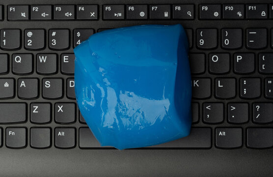 Blue slime placed on a black laptop keyboard in a home office