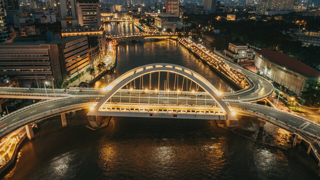 Illuminated Binondo-Intramuros Bridge aerial view over Pasig River at night in Manila, Philippines