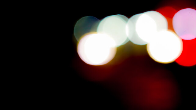 Creative abstract night background featuring soft out of focus bokeh lights with vibrant red and white glowing circular patterns on black