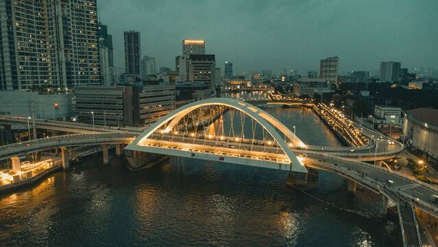 Illuminated Binondo Intramuros Bridge aerial view over Pasig River and Manila cityscape at night, Philippines