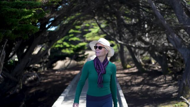 Mature woman strolls along the boardwalk at Mac Kerricher State Park enjoying the view near Fort Bragg and Mendocino California.