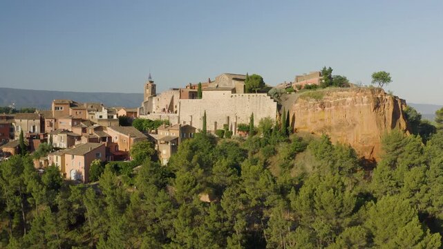 Aerial static footage revealing ochre stone houses and red tile roofs in Roussillon village, Provence, high angle shot