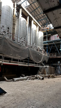 Inside an abandoned factory: silos, a safety net, and pipes lying on the floor.