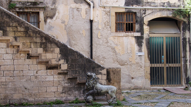 Stone lion statue and staircase in a historic courtyard in Ortigia, Syracuse, Sicily, Italy